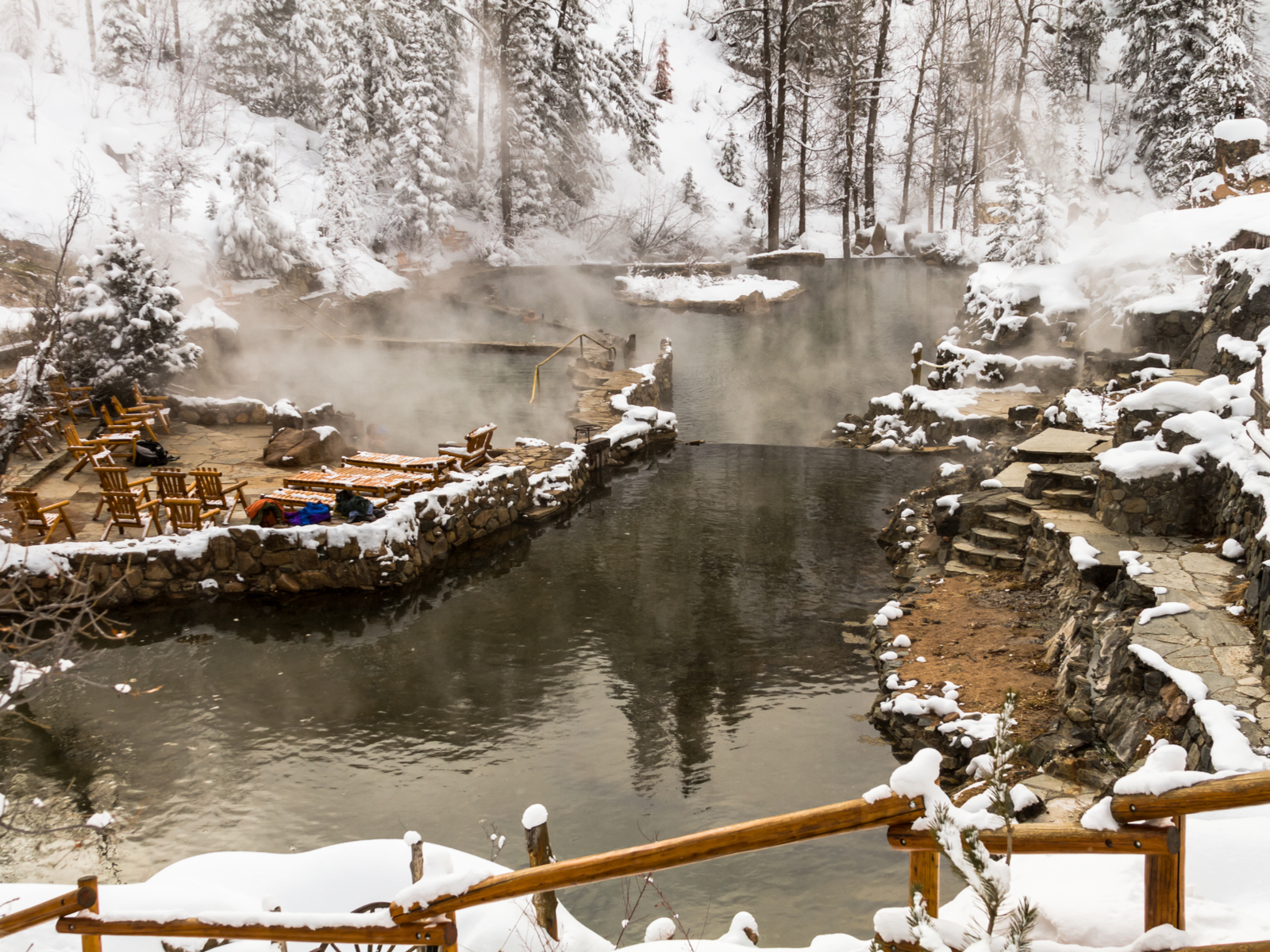 Photo of the Strawberry Park natural springs, one of the best hot springs in Colorado, in the winter with steam rising off the water