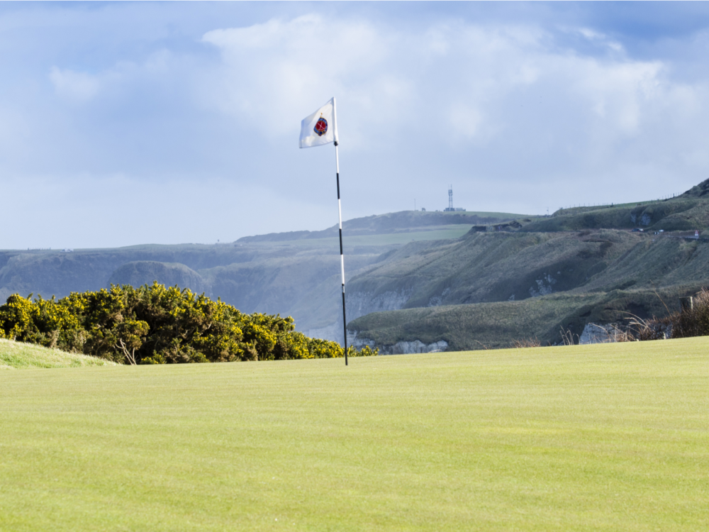 Beautiful golf course landscape with a raised white flag at Royal Portrush Golf Club, one of the best golf courses in Ireland