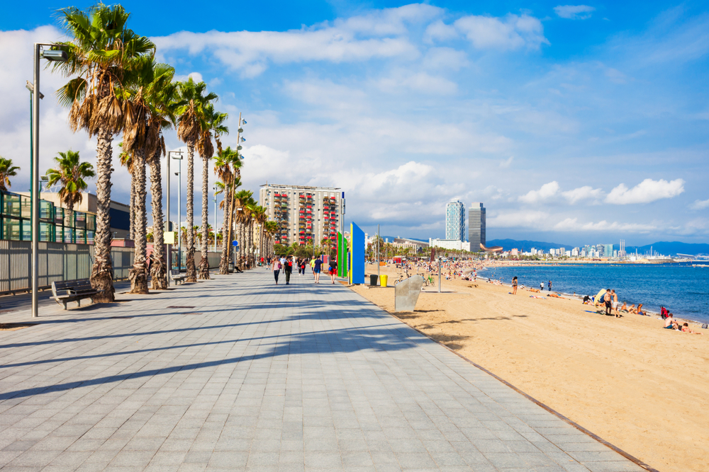Photo of Playa de la Barceloneta pictured with people roller blading and walking along the street