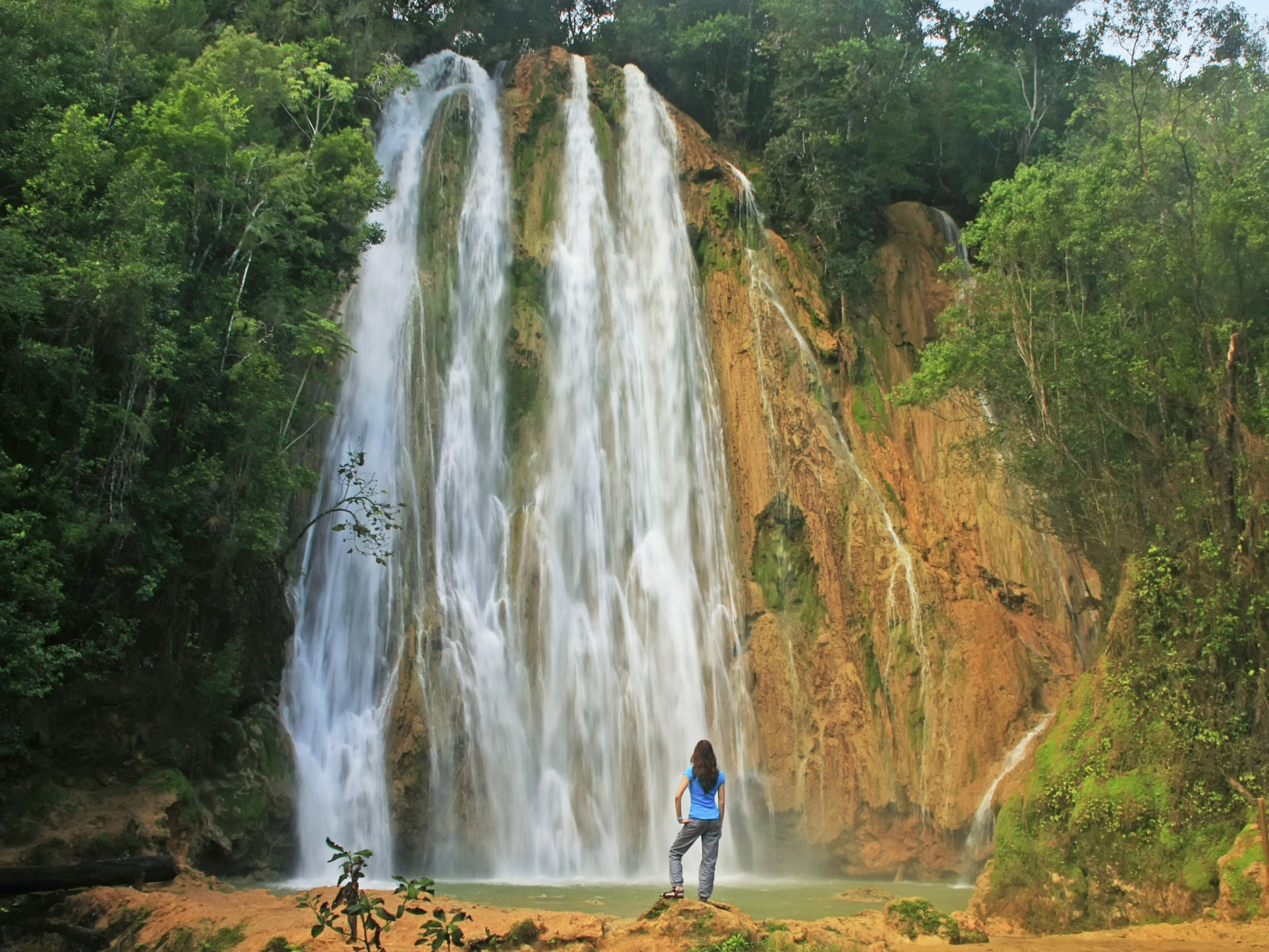 Woman standing in front of the El Limon waterfall, one of the must-visit places in the Dominican Republic