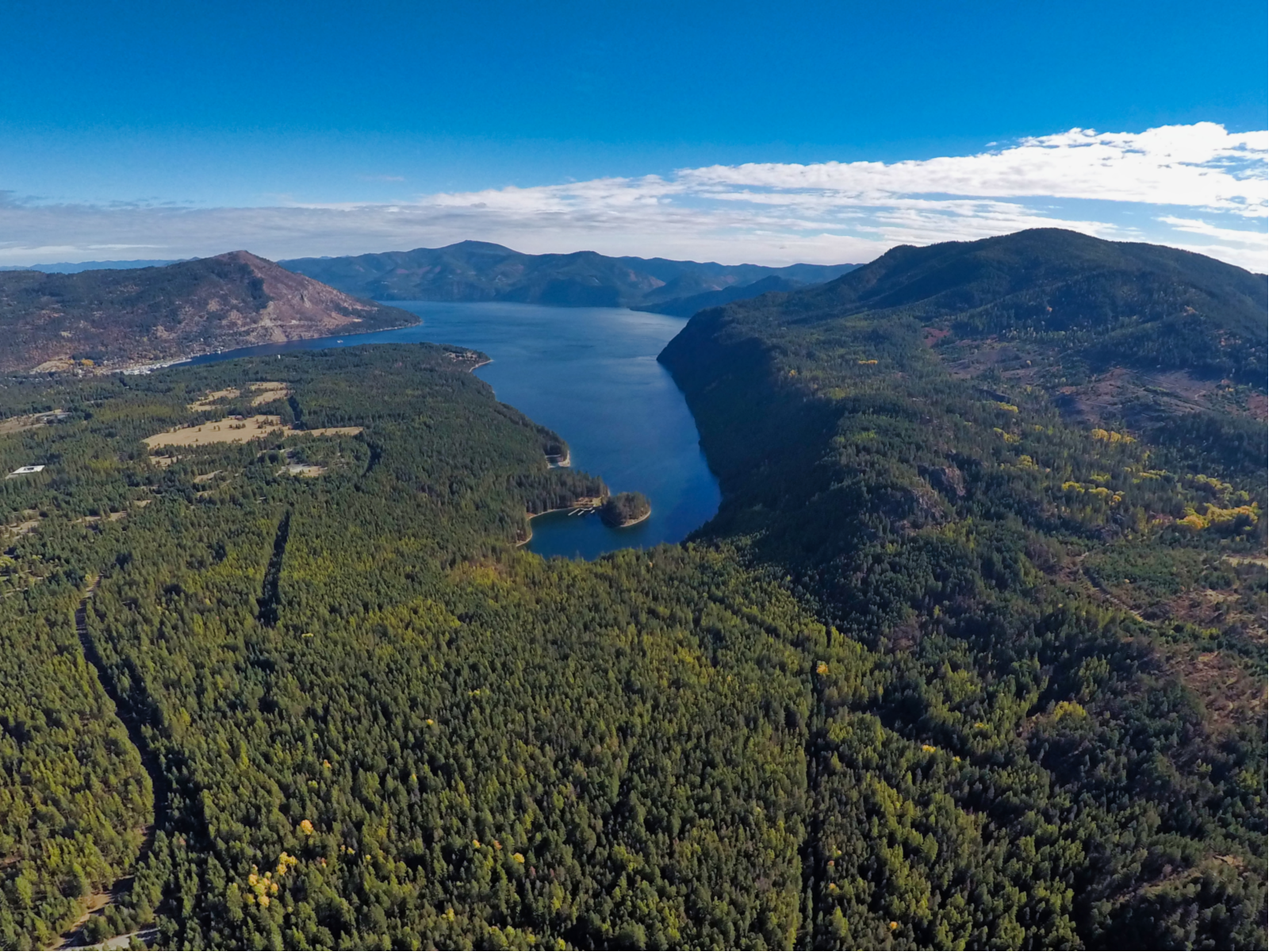Aerial view of the thick forest surrounding Lake Pend Oreille and Farragut State Park with its mountain skyline, one of the best things to see in Idaho