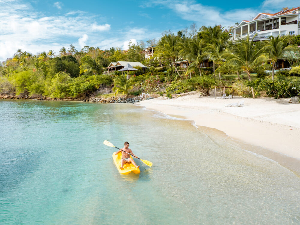 Man in yellow kayak on the water in front of one of the best resorts in Saint Lucia