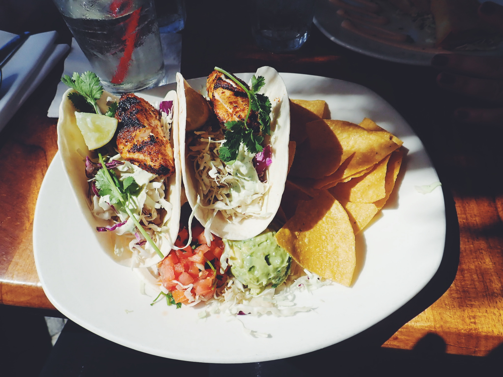 Delicious Fish Tacos served with chips and minced vegetables on a white ceramic plate at Shaka Tacoz, known as one of the best restaurants in Kona, Hawaii