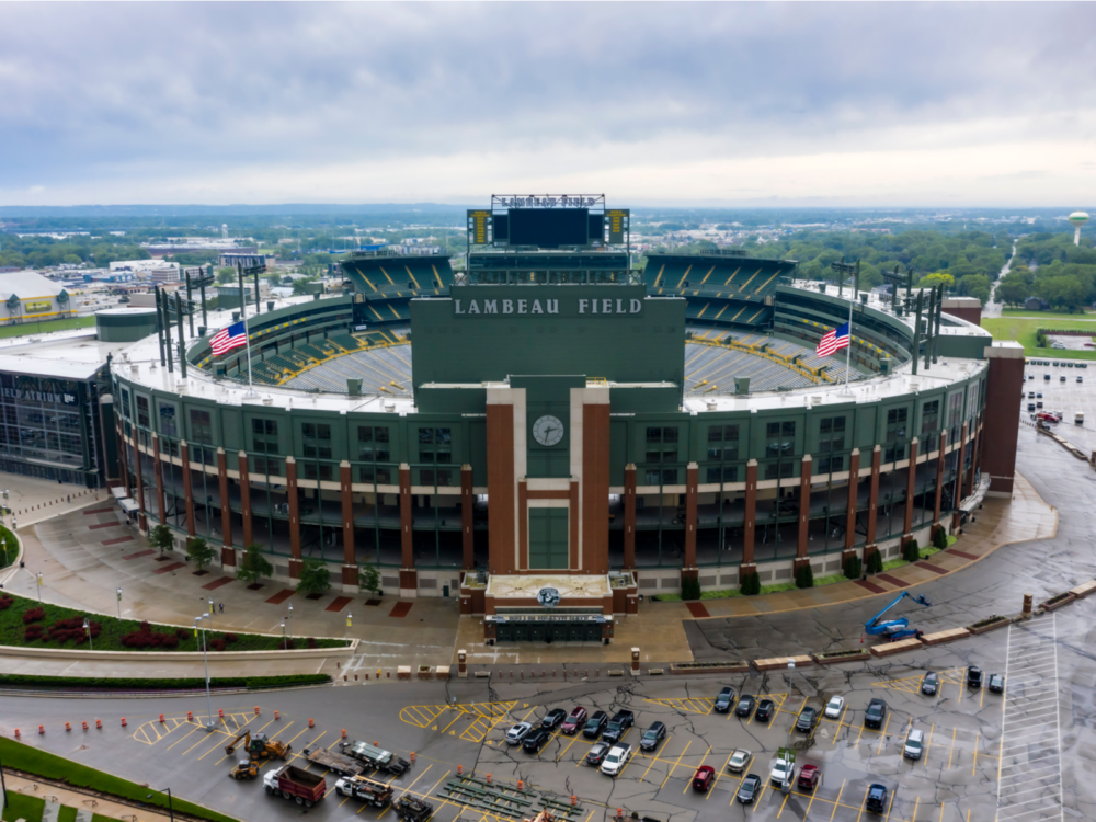 The historic humongous Lambeau Field in green paint that can accommodate thousand of people, one of the best Wisconsin tourist attractions, with cars parked in front