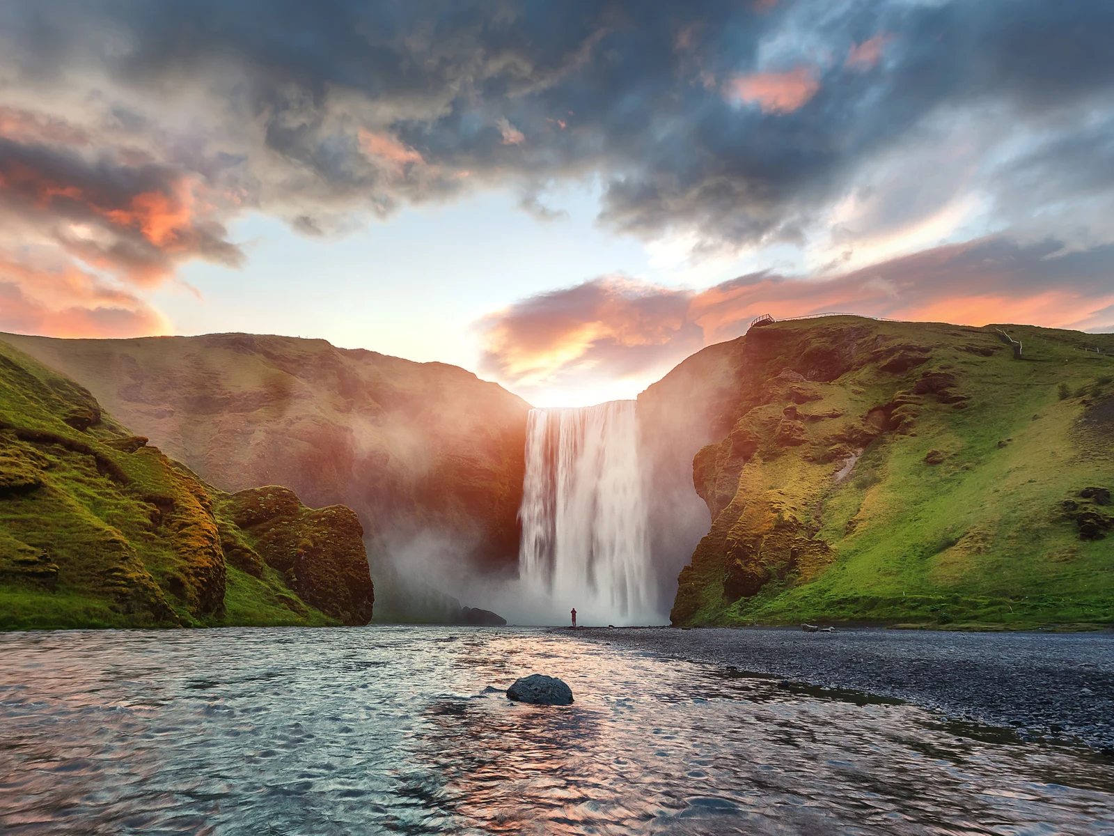 Skogafoss Waterfall as seen on one of the best hikes in Iceland at dusk with lush greenery around the falls