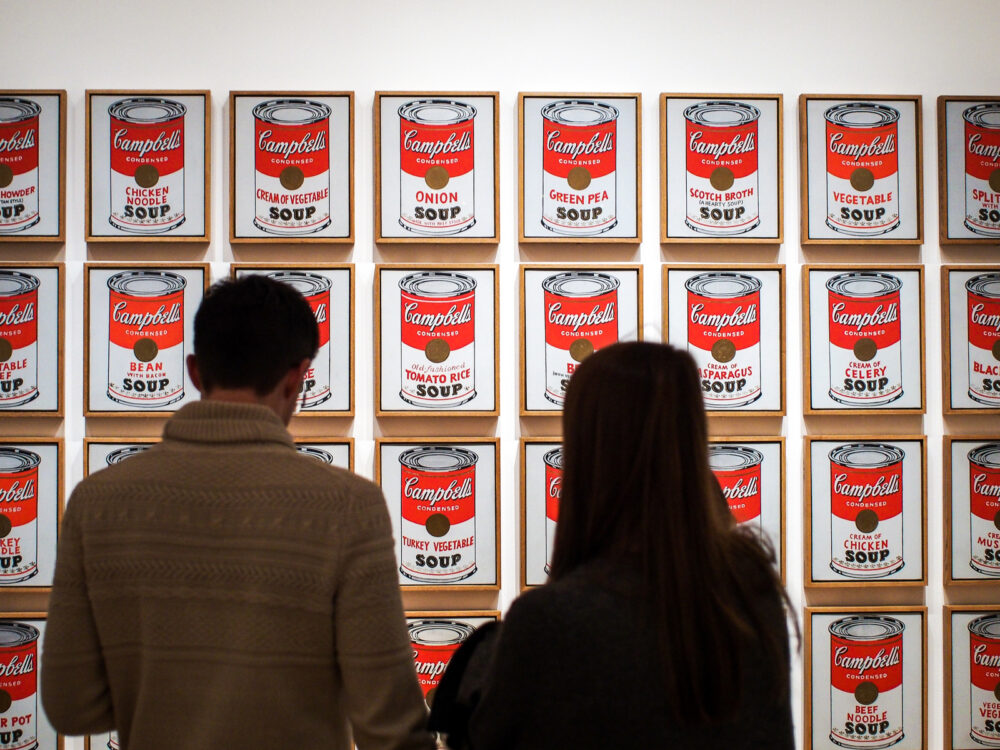 A couple observing the famous pop art by Andy Warhol titled Campbell's Soup Cans, one of the best things to do in Pennsylvania