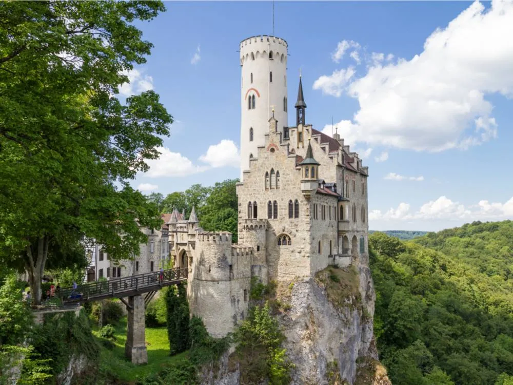 Tourists passing through a small wooden ramp at the entry of Lichtenstein Castle, one of the best castles in Germany, that sits on a boulder encircled by dense forest