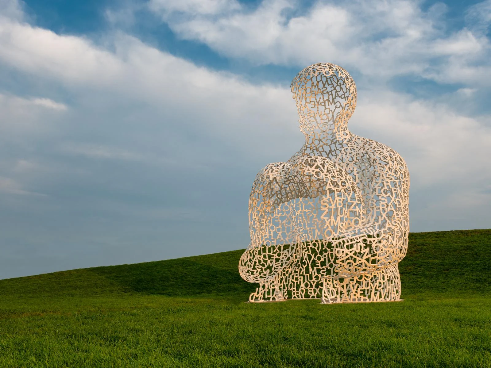 An abstract sculpture of a man in squatting position formed from connected letters entitled Nomad by Jaume Plensa, our pick for what to see in Iowa, at Pappajohn Sculpture Park
