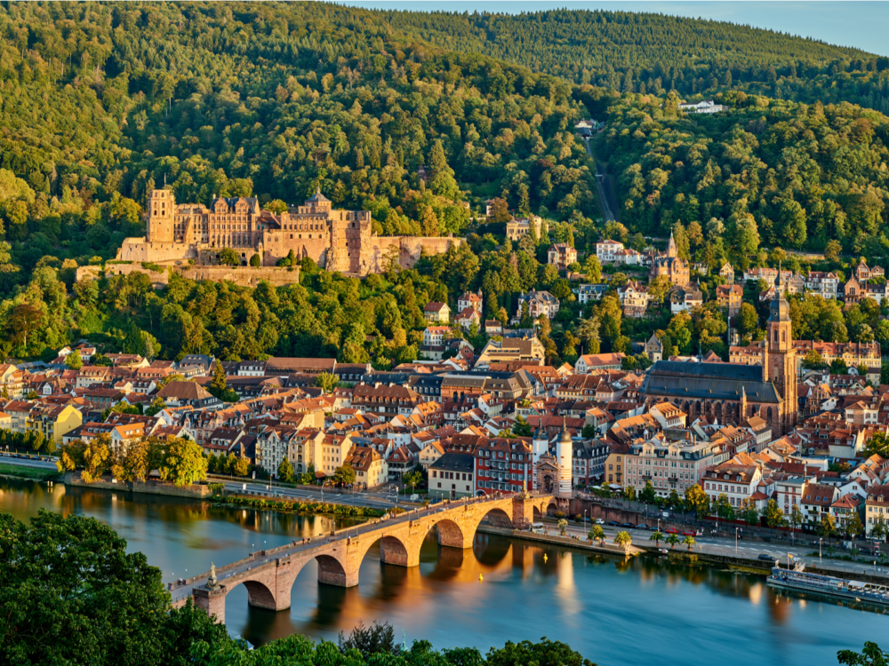 The gigantic Heidelberger Castle, a piece on the best castles in Germany, sits above Heidelberg town, seen with the famous old Karl Theodor Bridge crossing the Neckar River