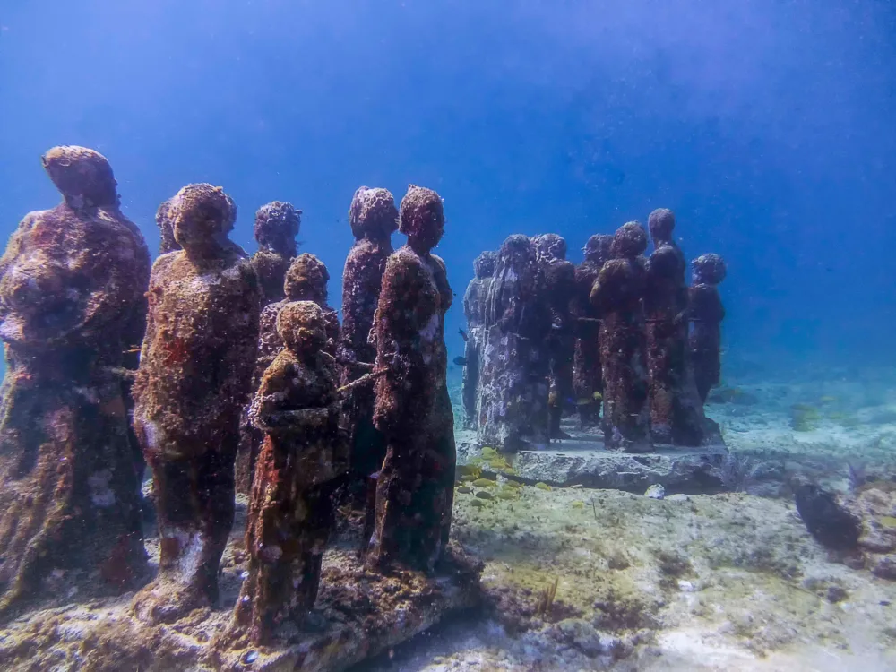 Mesmerizing statue of people covered with algae and submerged deep underwater is one of the best things to do in Cancun at Museo Subacuático de Arte also known as MUSA