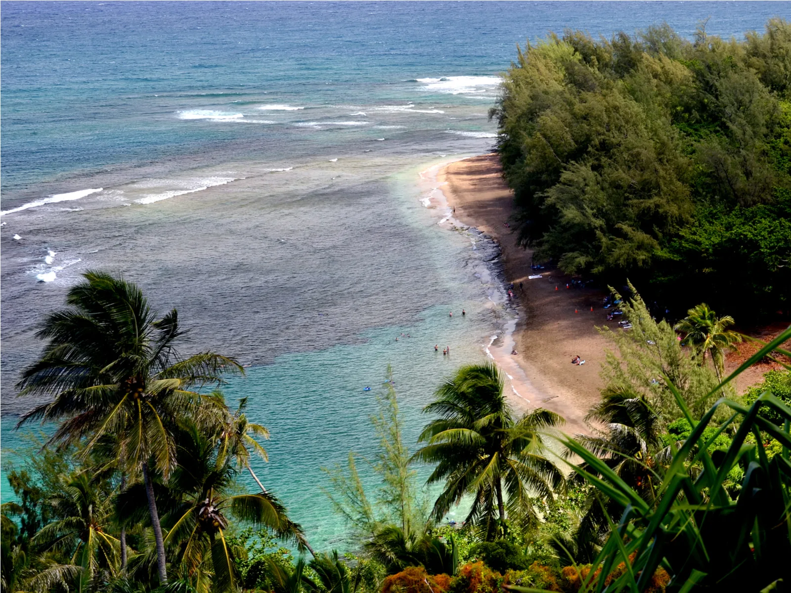 Aerial view on one of the best snorkeling spots in Hawaii, Ke’e Beach where few people are seen enjoying the calm shore