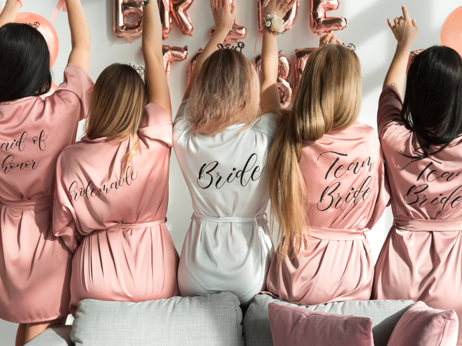 The bride with her girlfriends in silk robes as they raised their hands at a bachelorette party in one of the best bachelorette Airbnbs