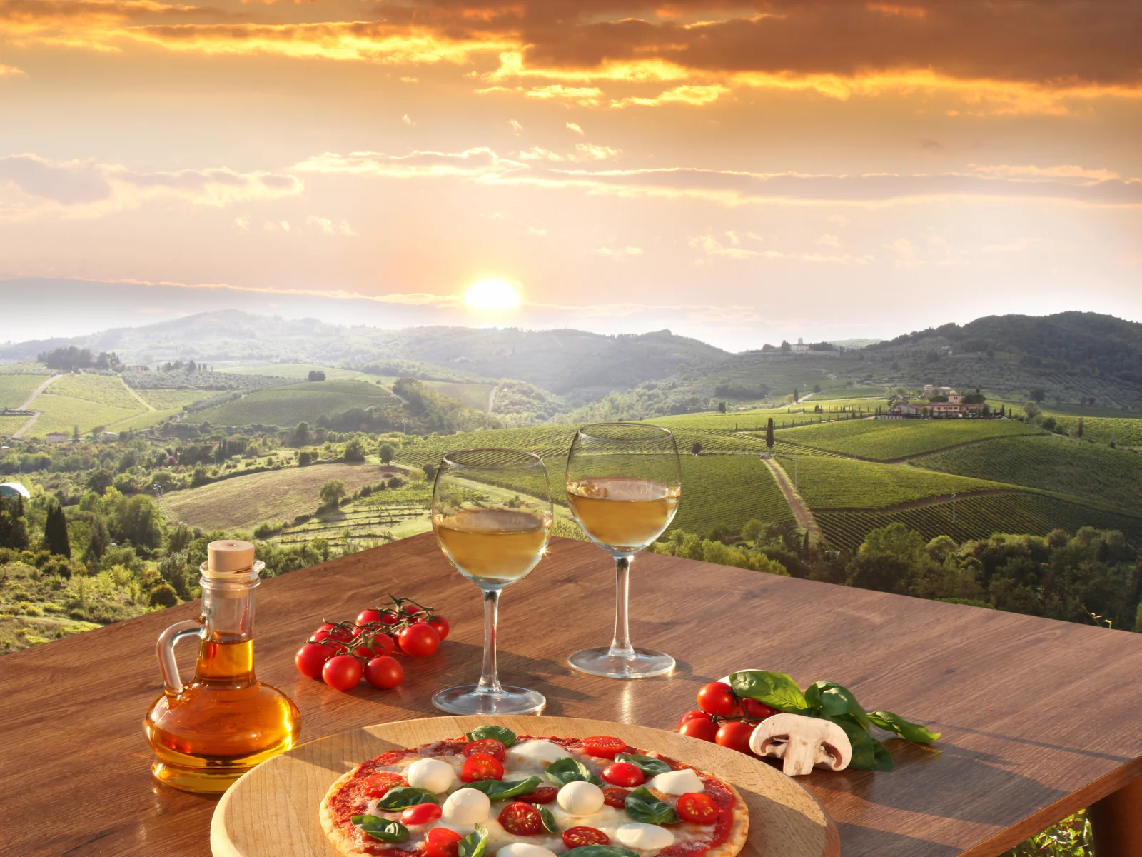 Wine glasses and appetizers overlook a gorgeous vineyard during the best time to visit Italy
