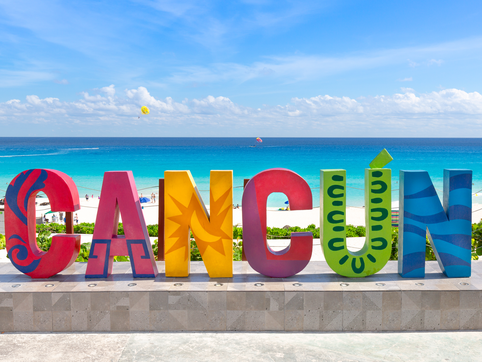 Vibrant monumental signage of Cancun with white sand beach, housing the best restaurants in Cancun, and a horizon in background