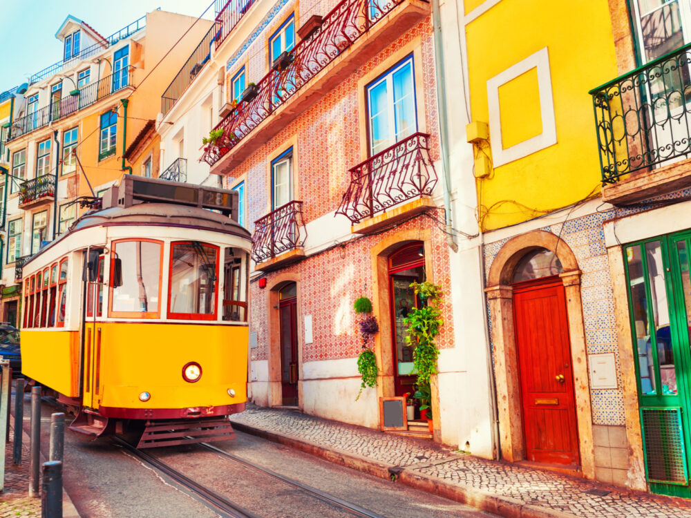 Yellow tram on a steep downhill track in one of the historic parts of the best places to visit in Portugal, Lisbon