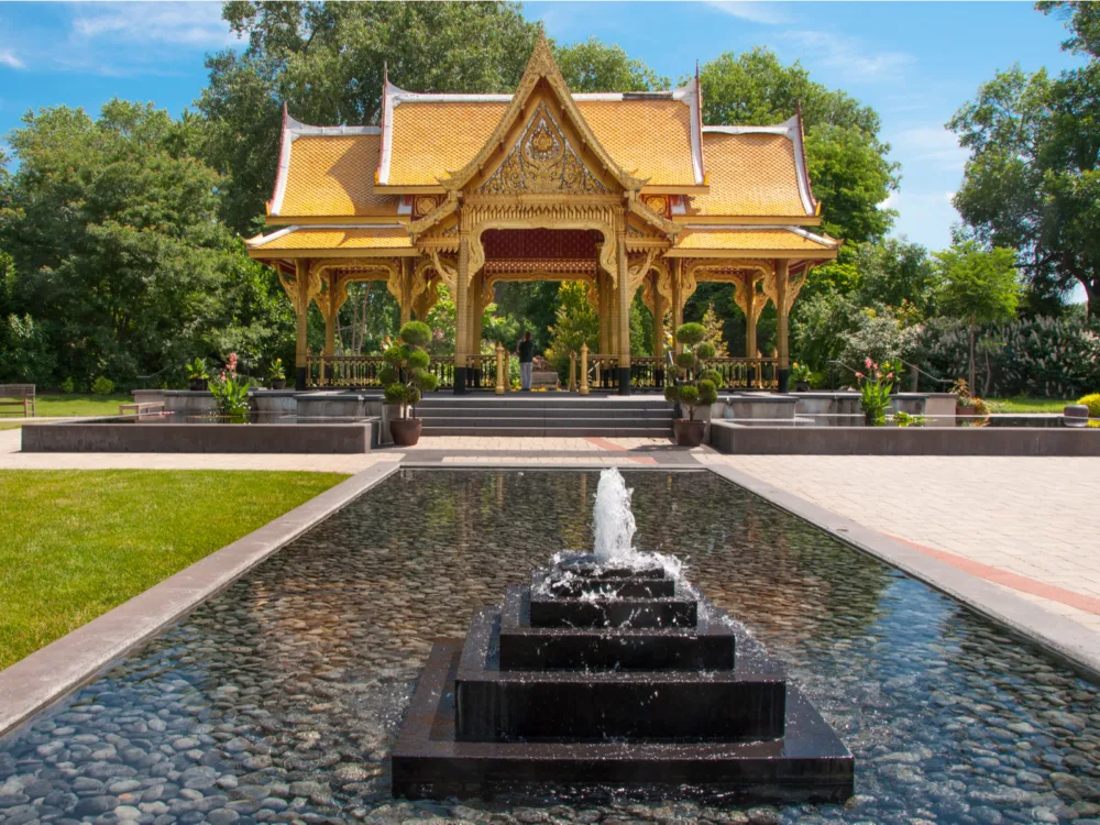 A fountain with black pebbles in front of the golden Thai Pavilion in Olbrich Botanical Gardens, one of the best Wisconsin tourist attractions