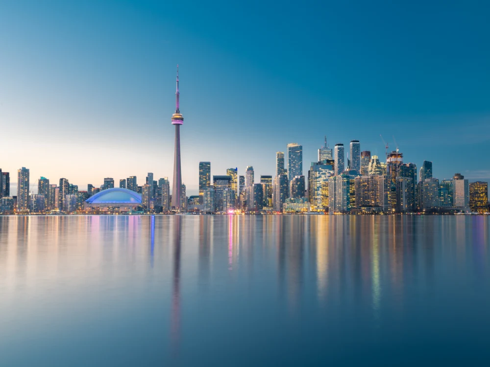 Illuminated Toronto City skyline reflected on the Lake Ontario at dusk, one of the best places to visit in Canada
