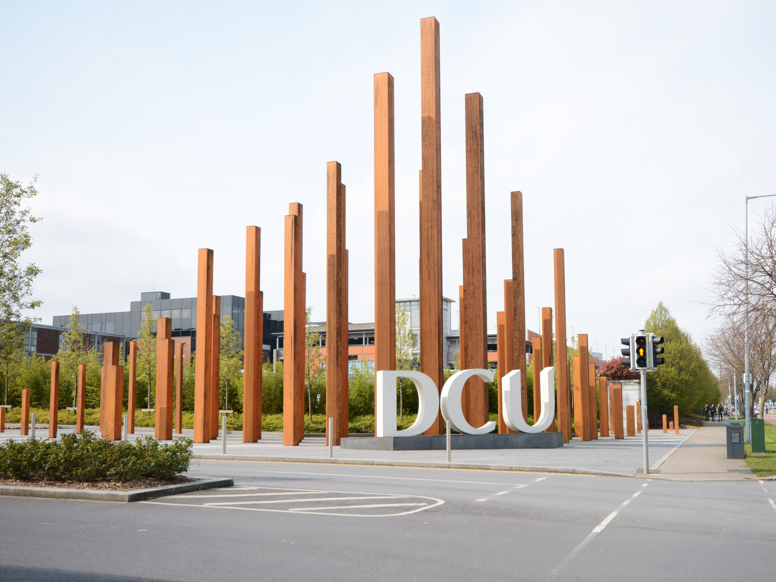 A modern wooden sculpture with large Dublin City University sign at one of the best universities in Ireland on the street side 