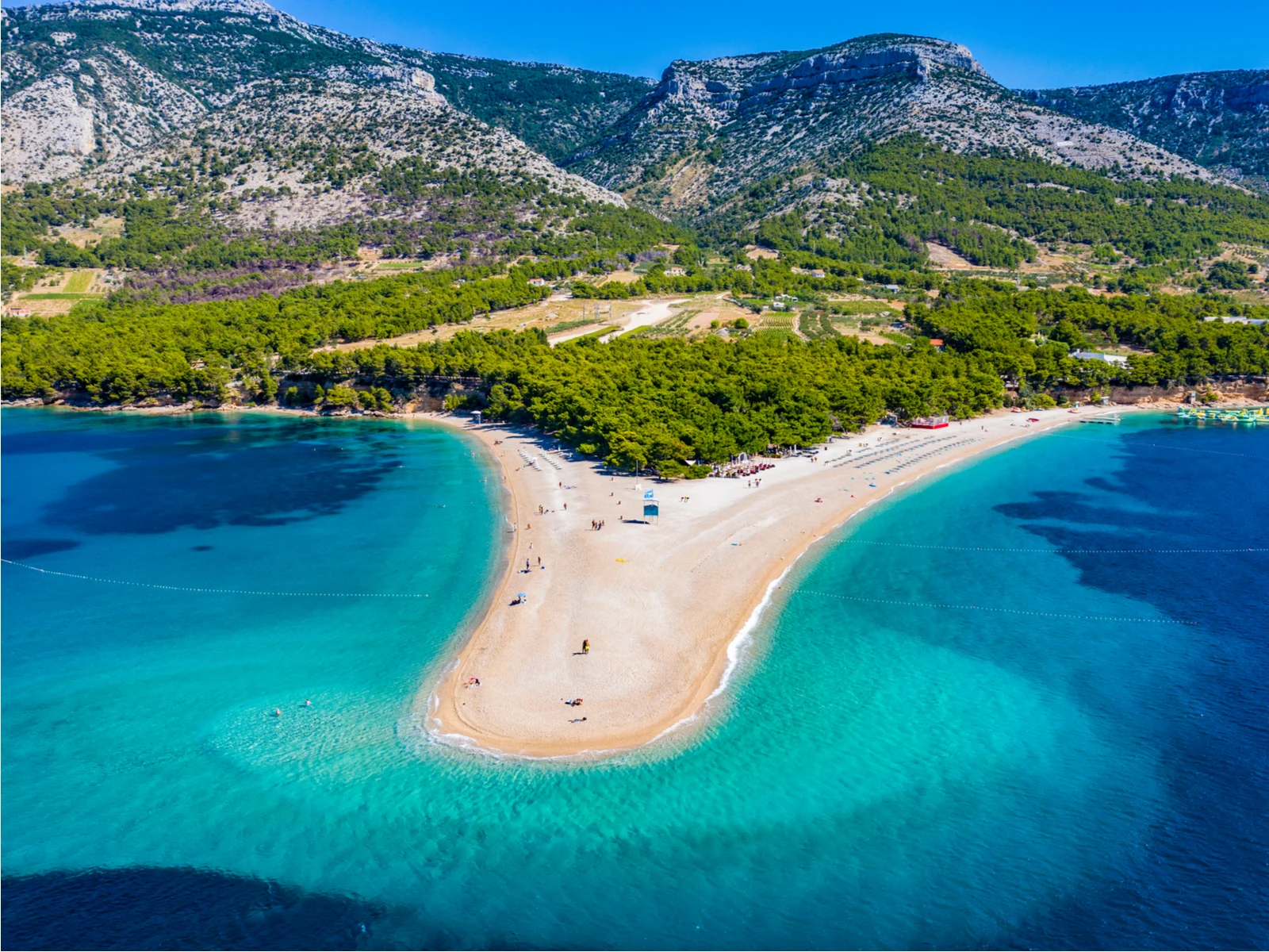 Zlatni Rat Beach, one of our top picks for things to do in Croatia, pictured from the air with the mountains in the background