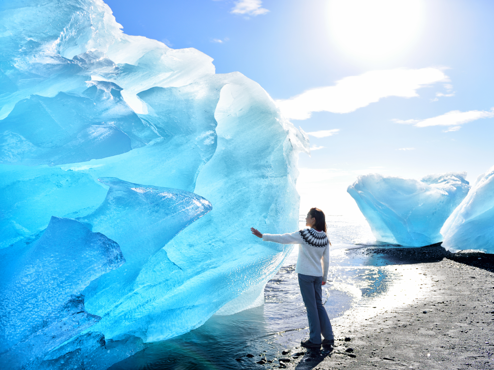 Woman touching a glacier in Jokulsarlon, one of Iceland's best hikes