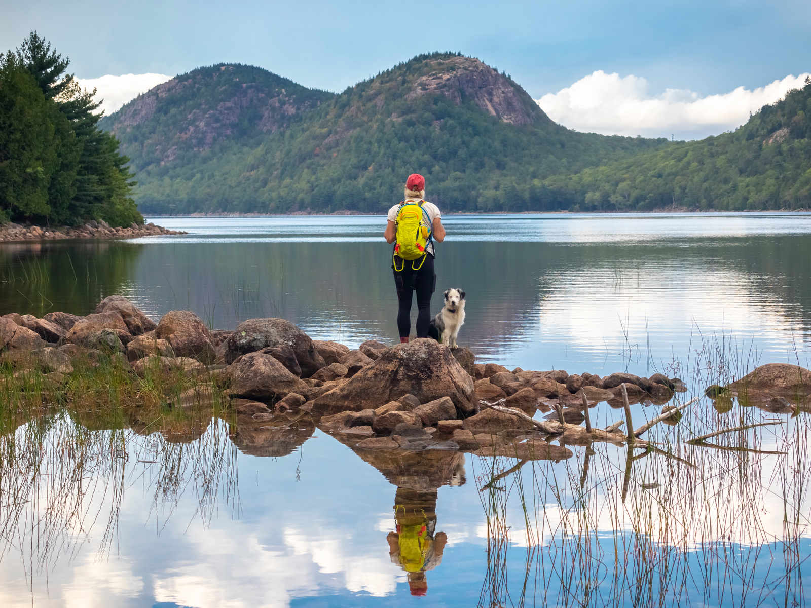 Woman hiking with a dog in Acadia during the best time to visit Maine
