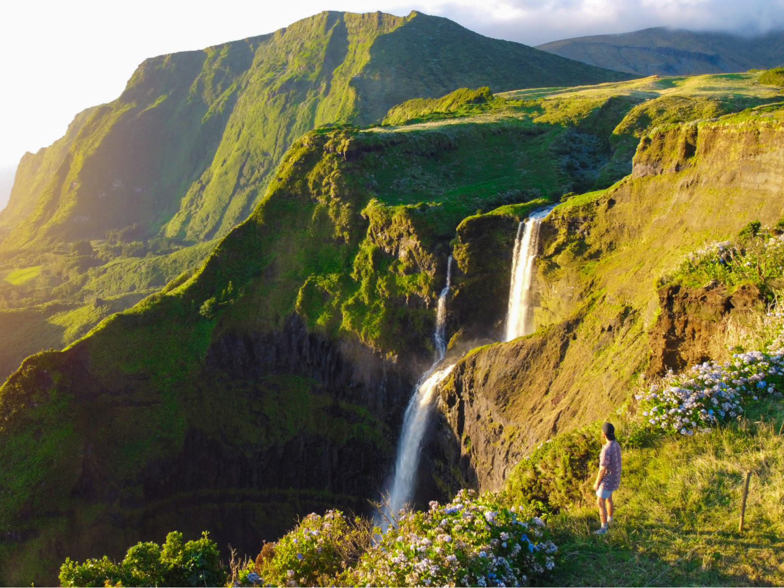 Woman overlooking a waterfall in a lush paradise in the Azores, one of the best island vacations in the world