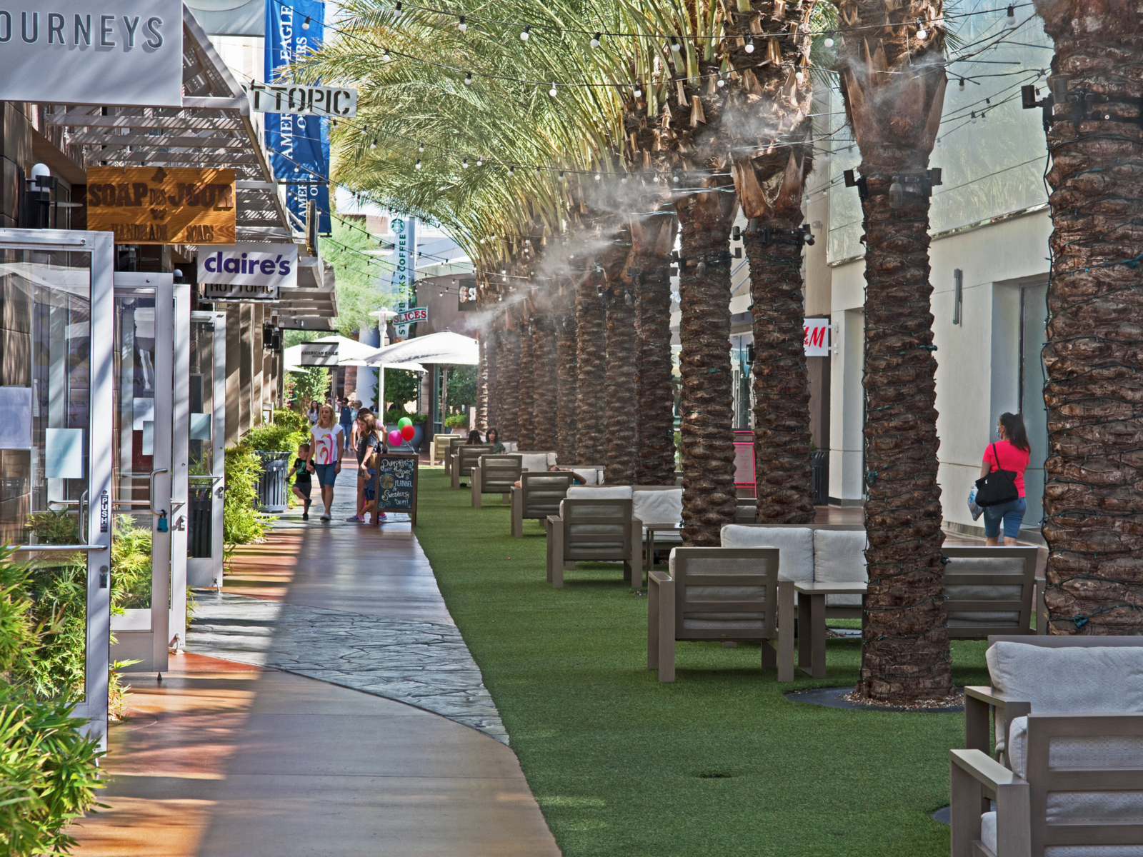 Shoppers walk between trees at a mall, one of the best things to do in Phoenix