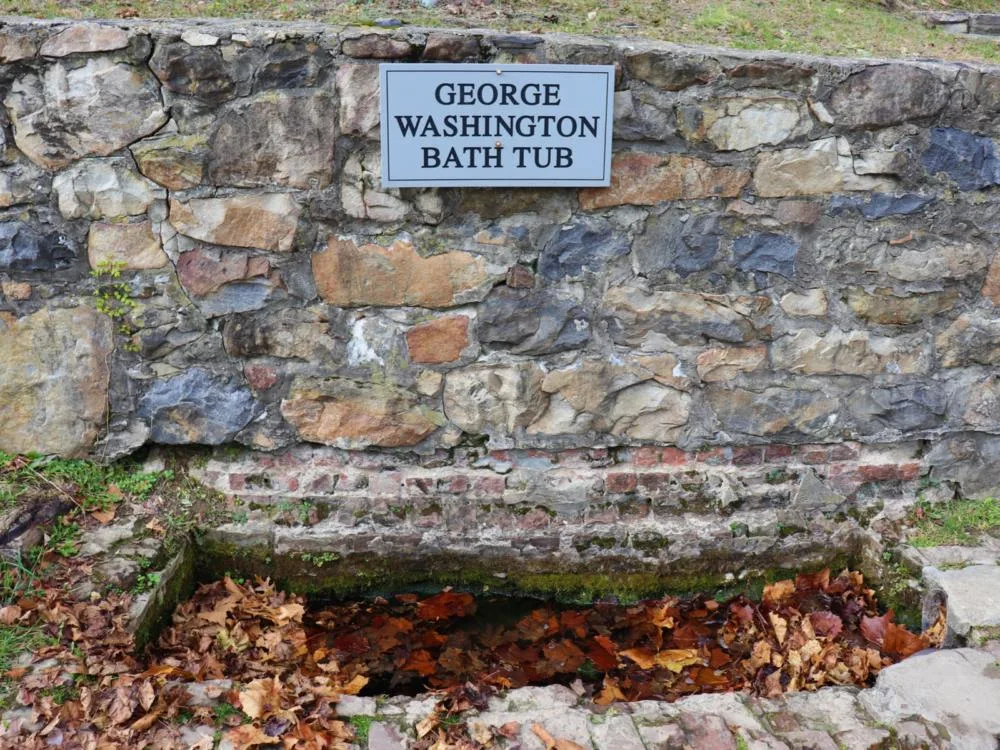The George Washington’s Bathtub beside a wall of rocks, with diluted water and dried leaves, is a natural spring and one of the best attractions in West Virginia