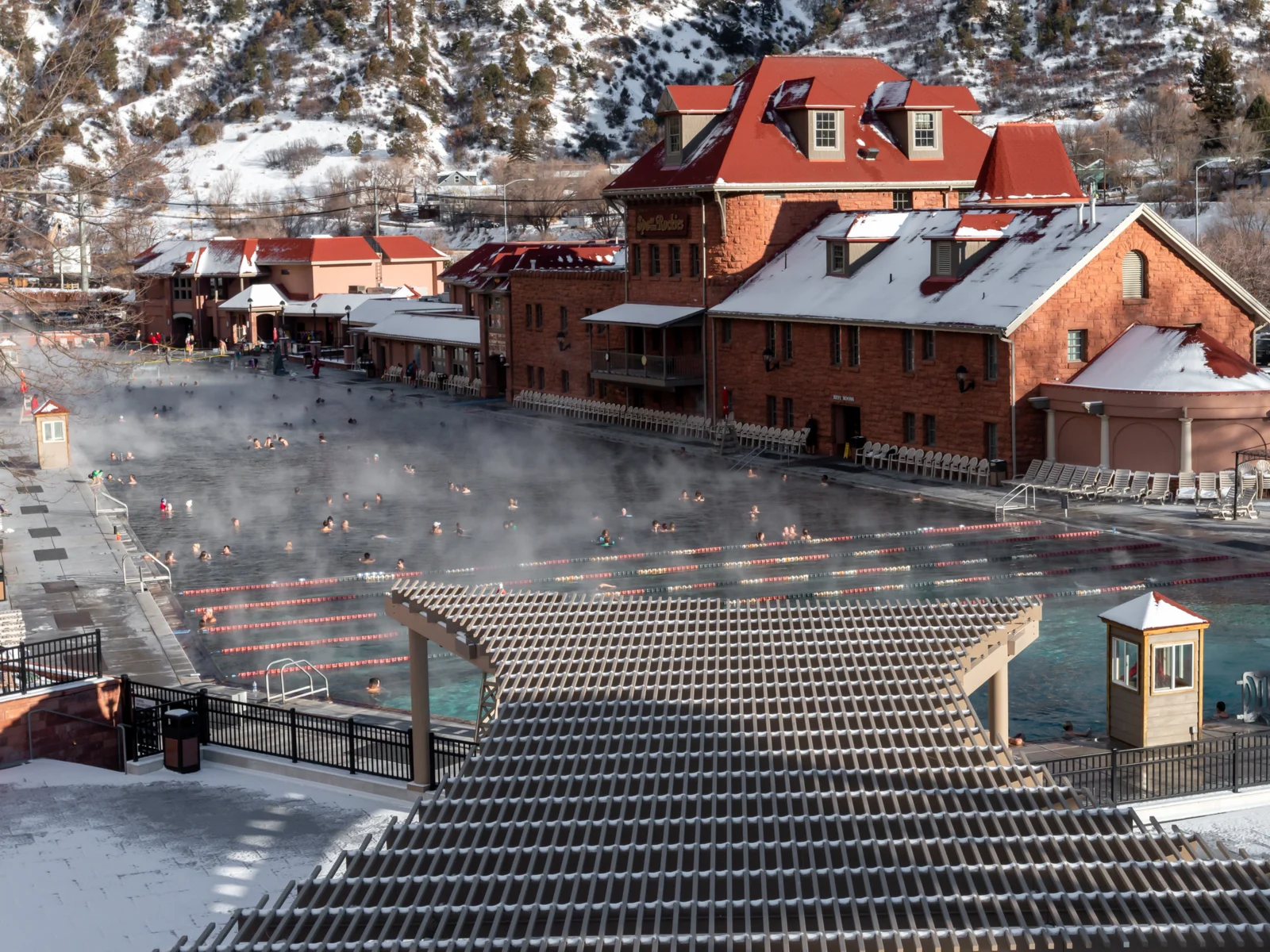 People sitting in the Glenwood Springs, one of the best hot springs in Colorado, while snow is on the ground all around
