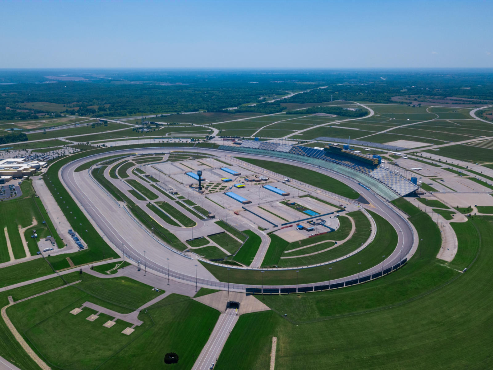 Aerial view of the vast oval auto racing Kansas Speedway, one of the best things to see in Kansas, with neat green landscape and curve roads