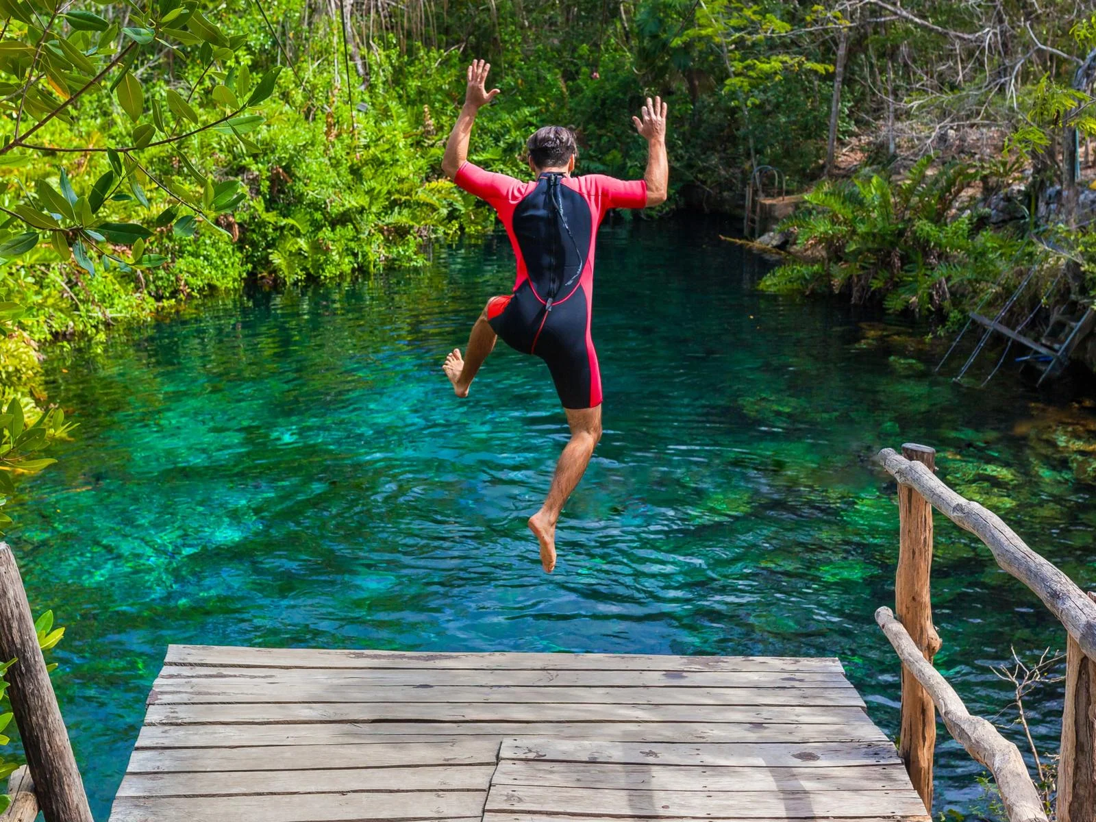 Man in a wetsuit jumping into one of the best cenotes in Mexico
