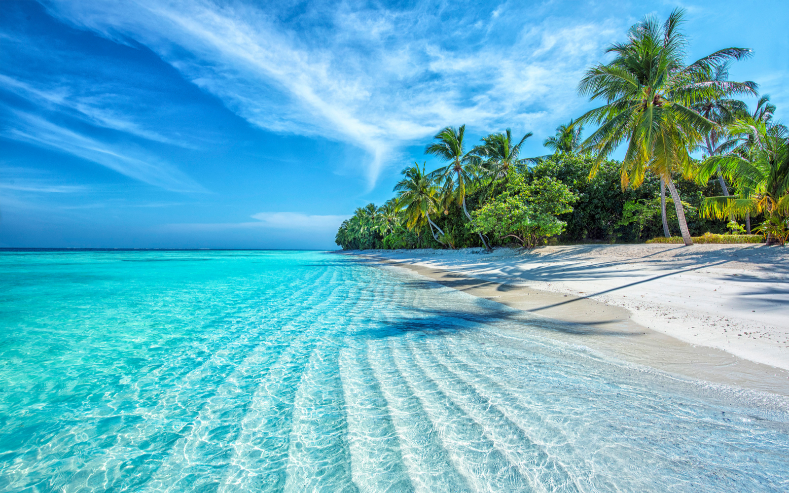 Gorgeous view of the Maldives, one of the best island vacations, pictured with rippling waves on the beach