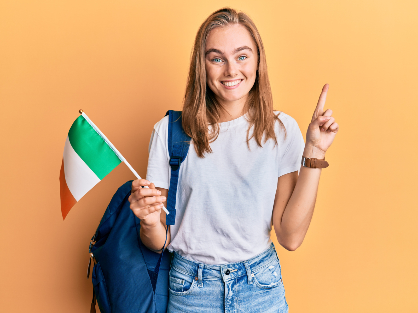Pretty blonde student holding a flag from her country to symbolize the best colleges in Ireland
