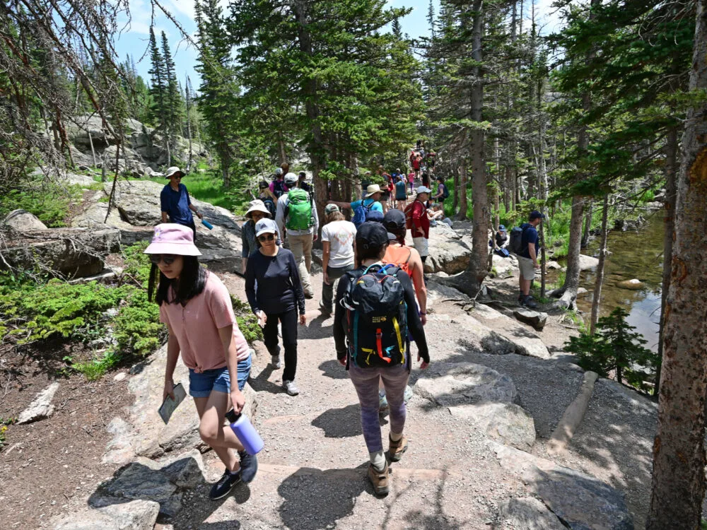 Hikers wearing hats and sunglasses trekking on crowded Emerald Lake Trail, one of the best hikes near Denver