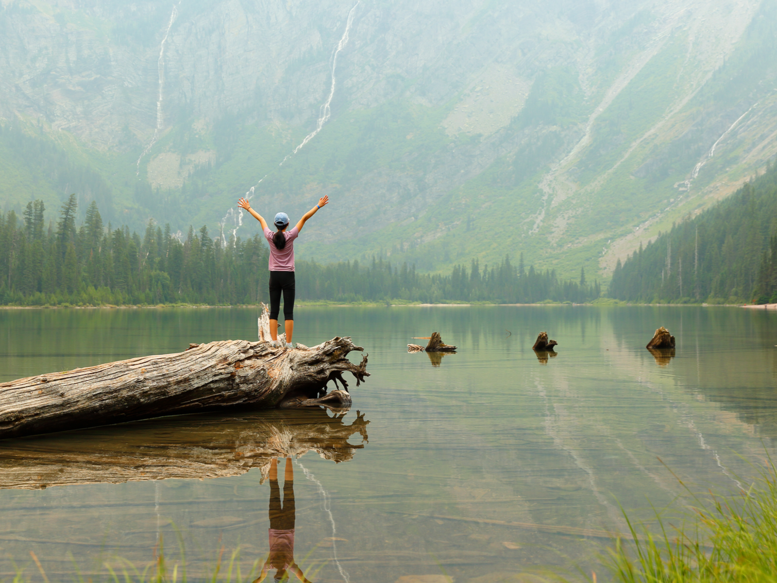 Young hiker throwing her arms up at Glacier, one of the best places to visit in Montana