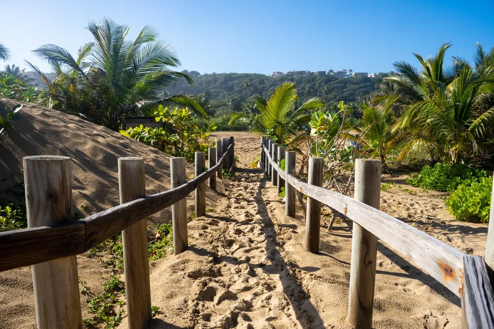 Wooden fence running along the beige sand Aguadilla Beach in Puerto Rico