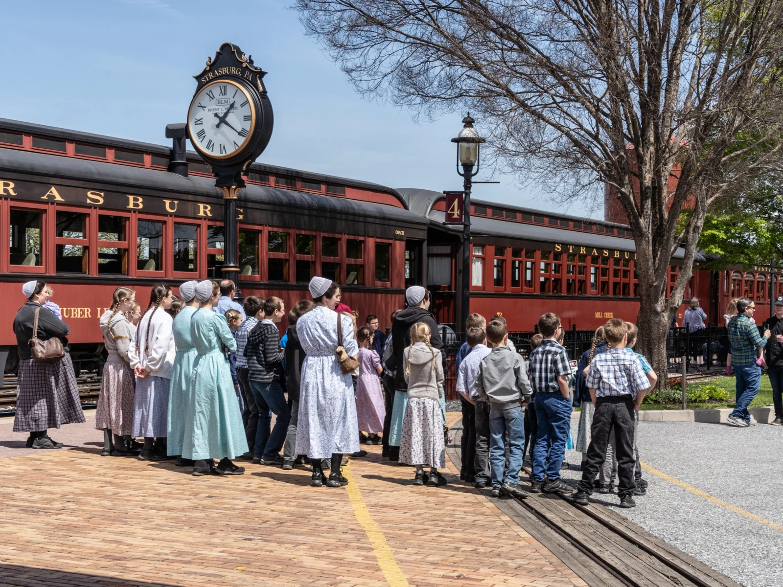 A group of Mennonite Women and children waiting for ride on one of the best things to do in Pennsylvania, the Strasburg Rail Road with red and black paint