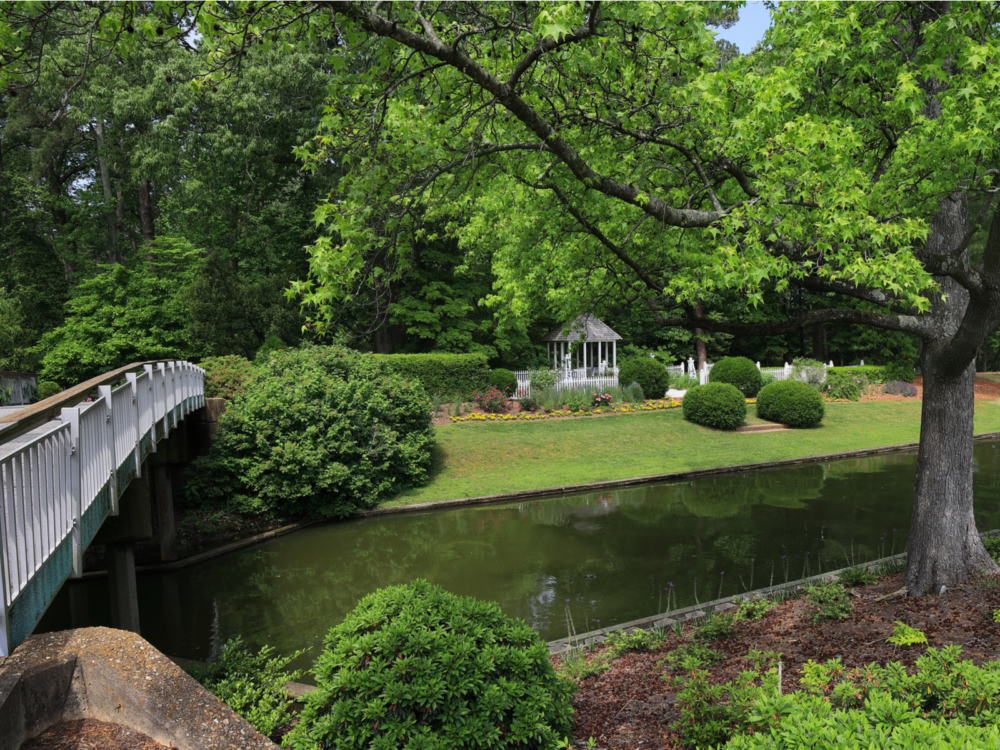 A small wooden bridge crossing a canal at Norfolk Botanical Garden, and seeing the scenic view of the colonial garden is one one of the things to do in Virginia