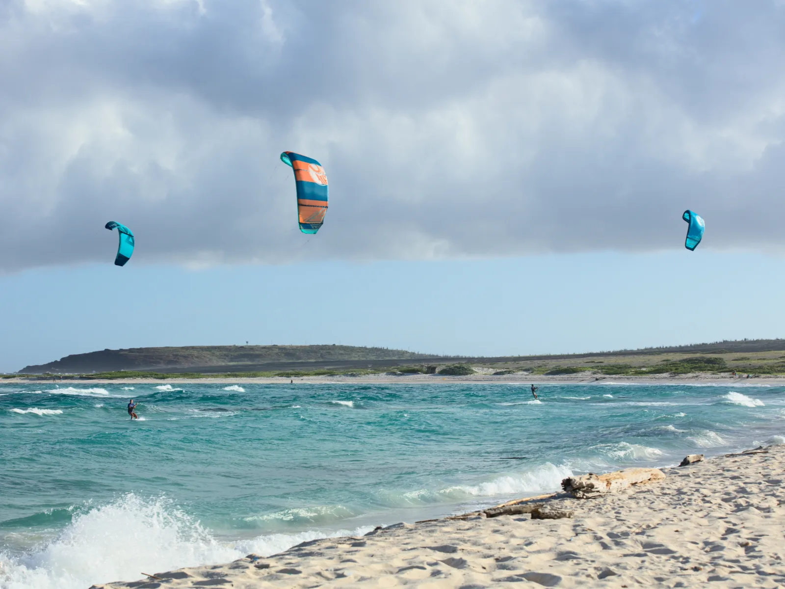 One of the best beaches in Aruba, Boca Grandi with tourists Kitesurfing on strong waves during a cloudy and windy day