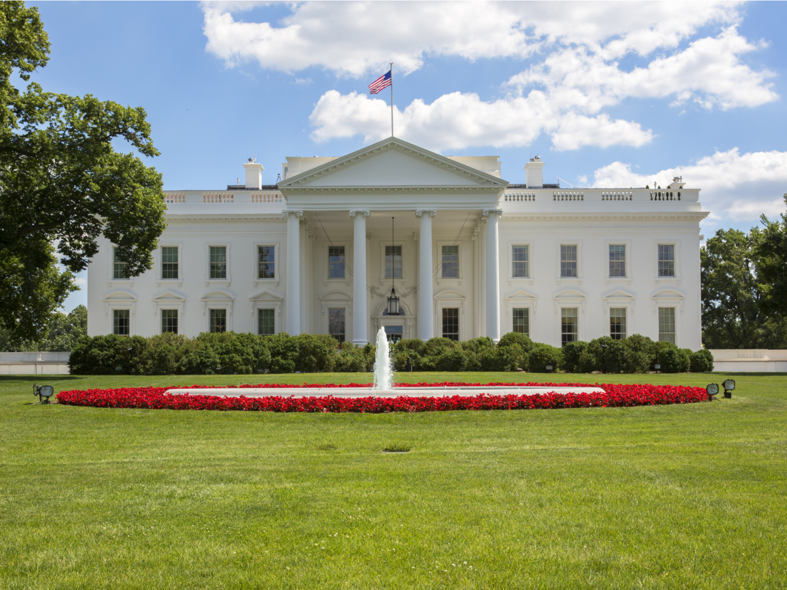 Front view of the White House lawn with a fountain and flowers outside for a piece on the best American landmarks