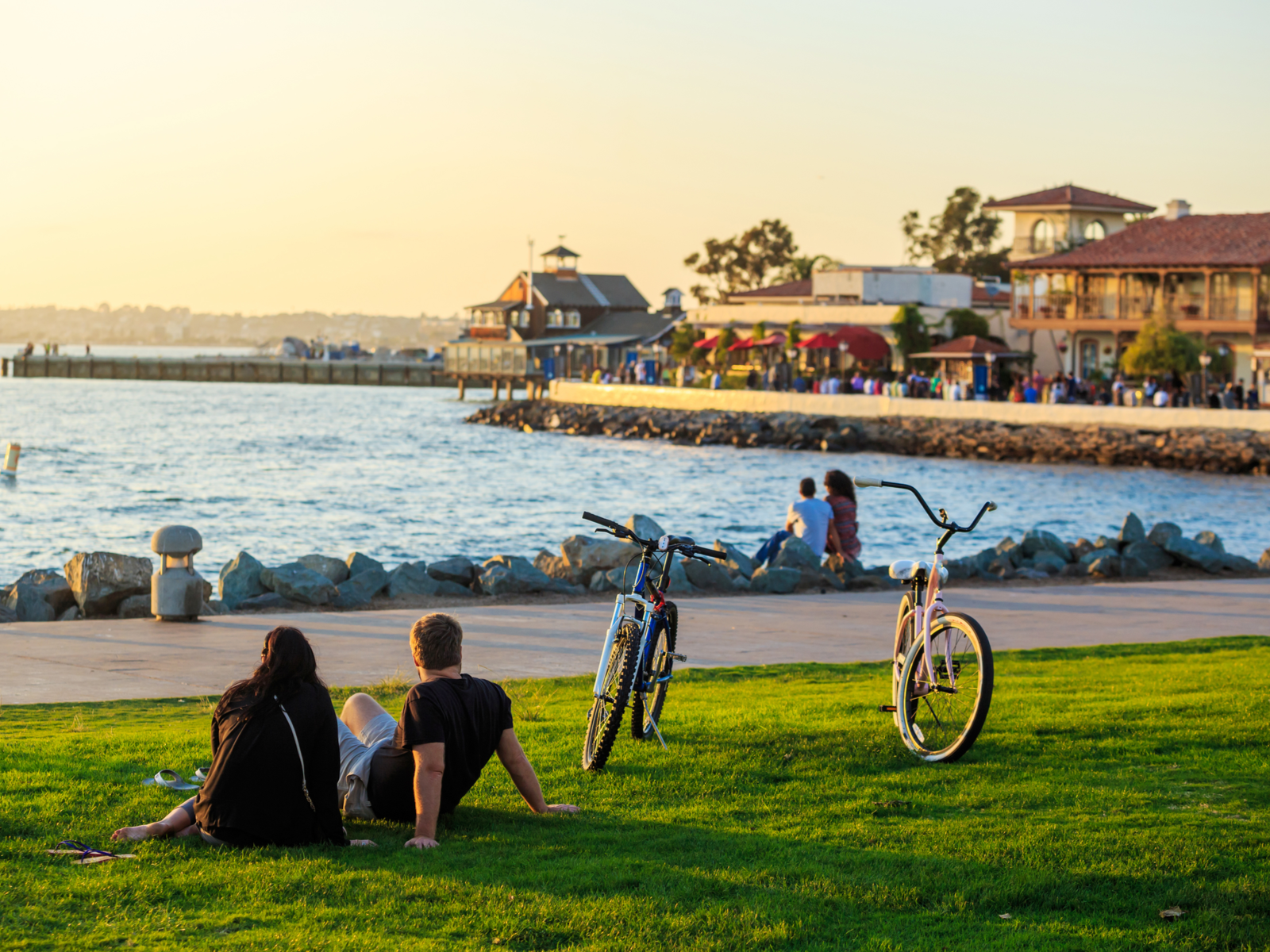 A young couple sitting on the waterfront park, one of the best things to do in San Diego, while the sun sets