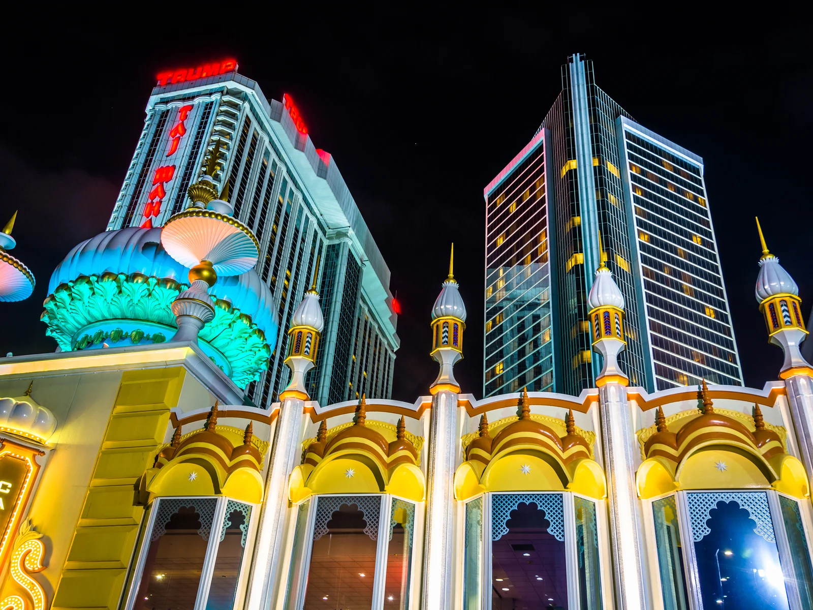 Worm's-eye view of the elegant hotel and casino Trump Taj Mahal at night, the place you should visit for casino hopping, one of the best things to do in New Jersey
