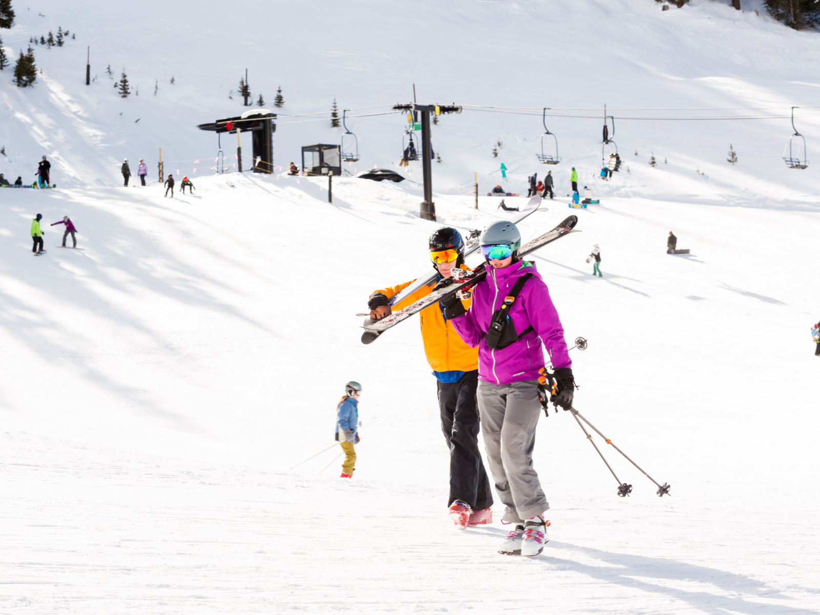 A couple lifting their ski on their shoulder and other skiers and snowboarders in background at Arapahoe Basin Ski Resort, one of the best ski resorts near Denver