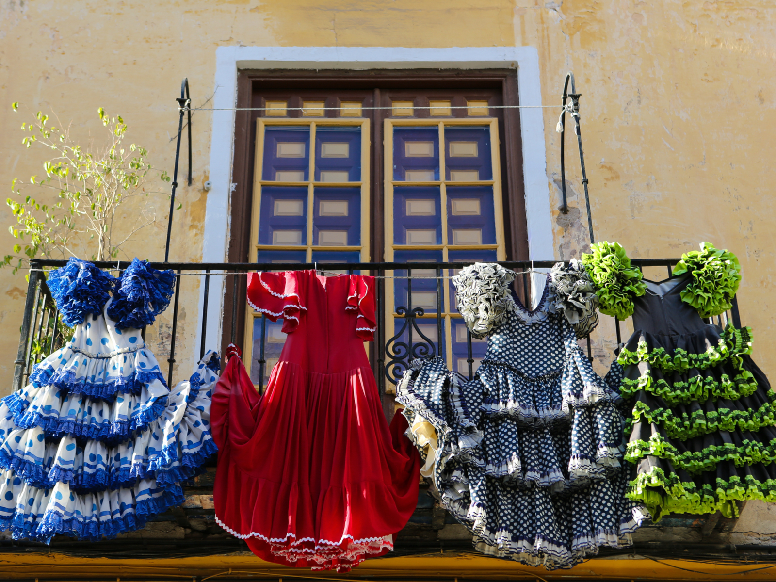 View of flamenco dresses hanging from the railing of a stucco-lined house during the best time to visit Barcelona