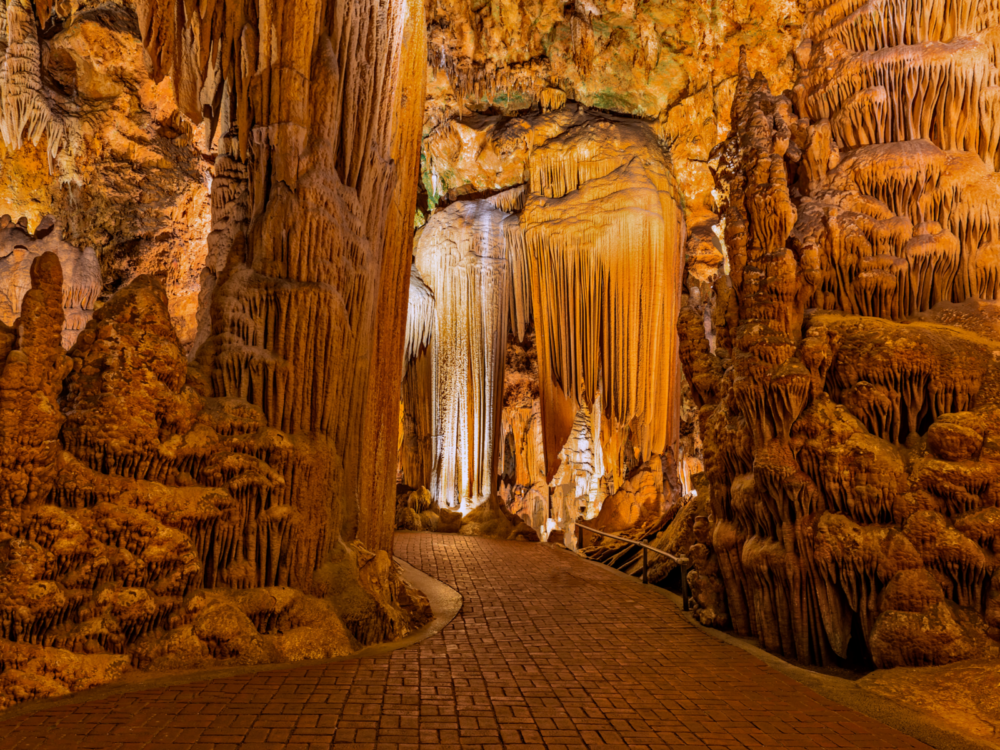 A brick path inside the Luray Caverns and walking beside majestic rocks formations is one of the things to do in Virginia