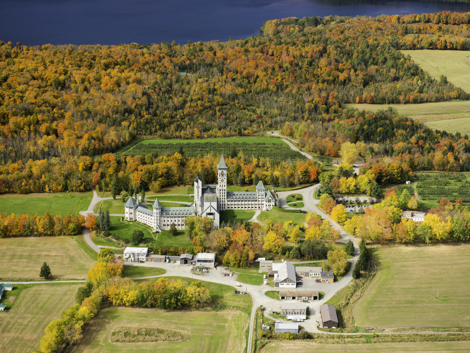 Aerial view of Saint Benoit du Lac Abbey and a lush forest during foliage season at Eastern Townships, Quebec, photographed as a piece on the best places to visit in Canada