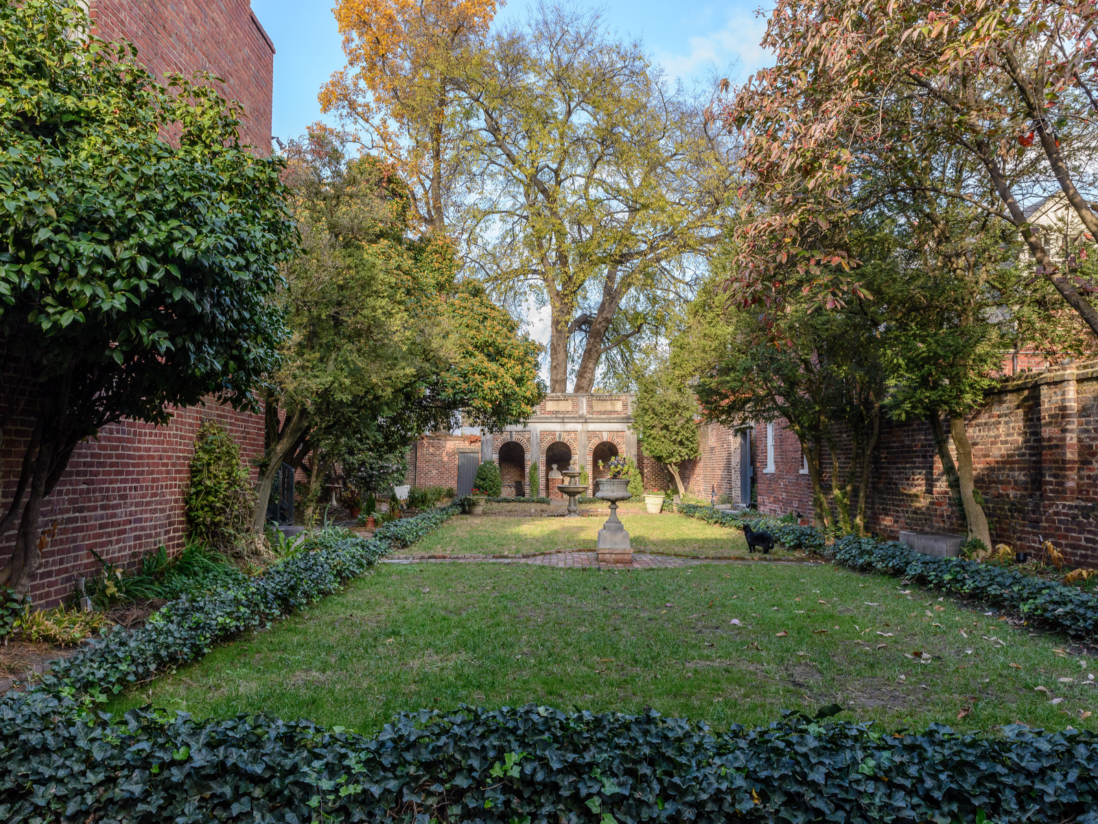 The rectangular garden of the Edgar Allan Poe Museum, one of the things to do in Virginia, with wall of bricks on each corner