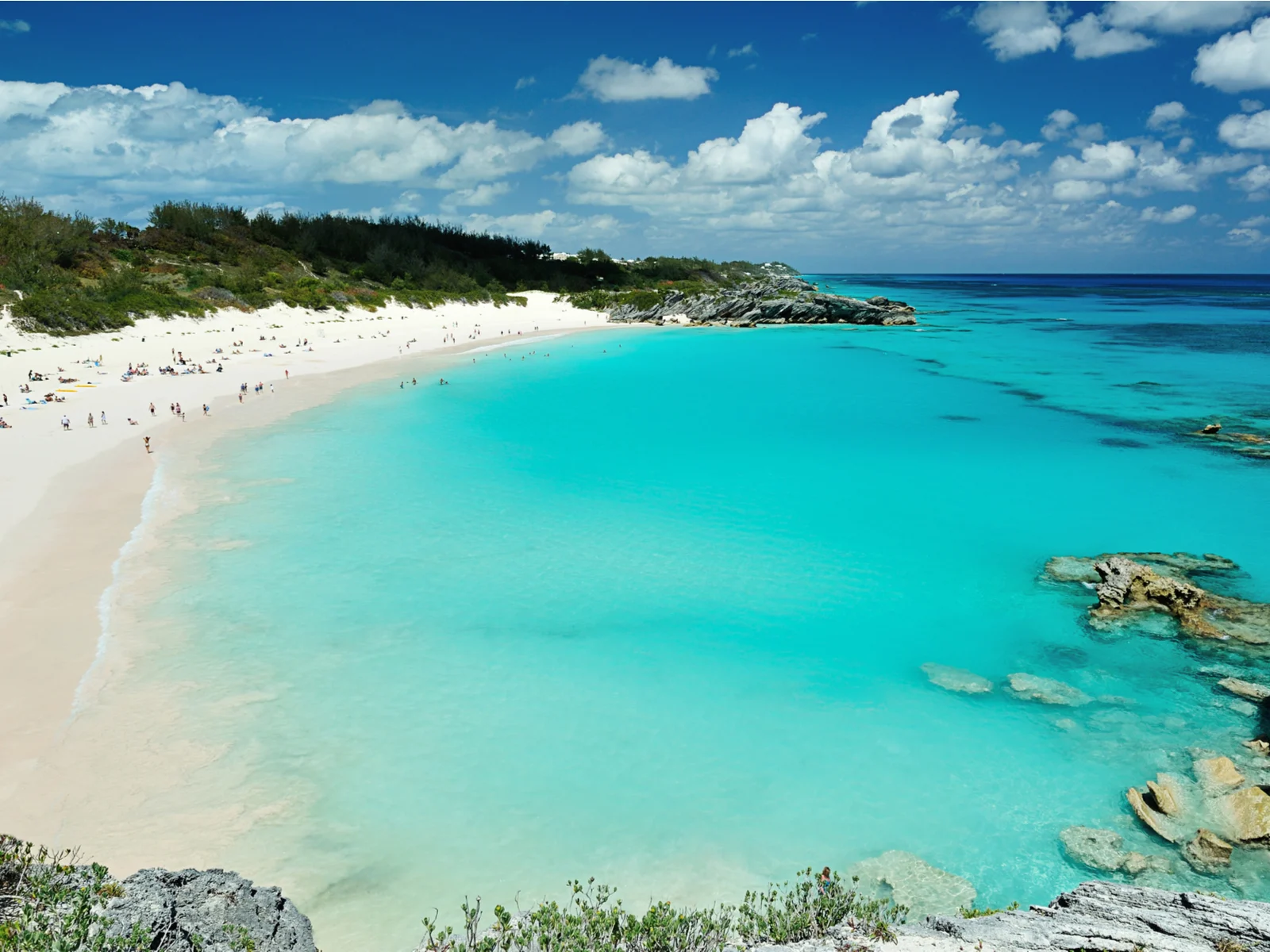 Gorgeous view of a bunch of folks on a white sand beach in Bermuda during the best time to visit