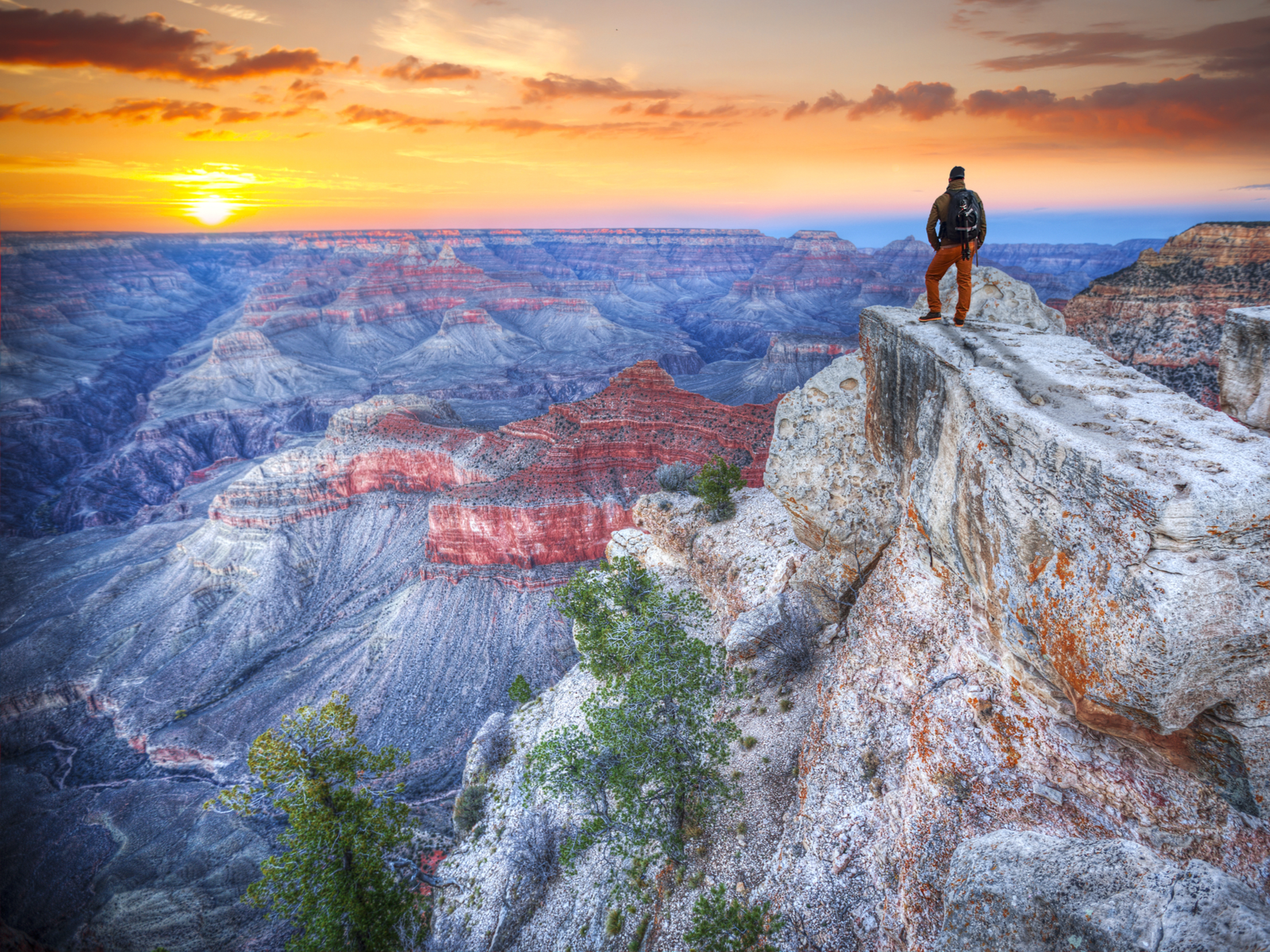 Man standing on a cliff at the Grand Canyon during the sunrise