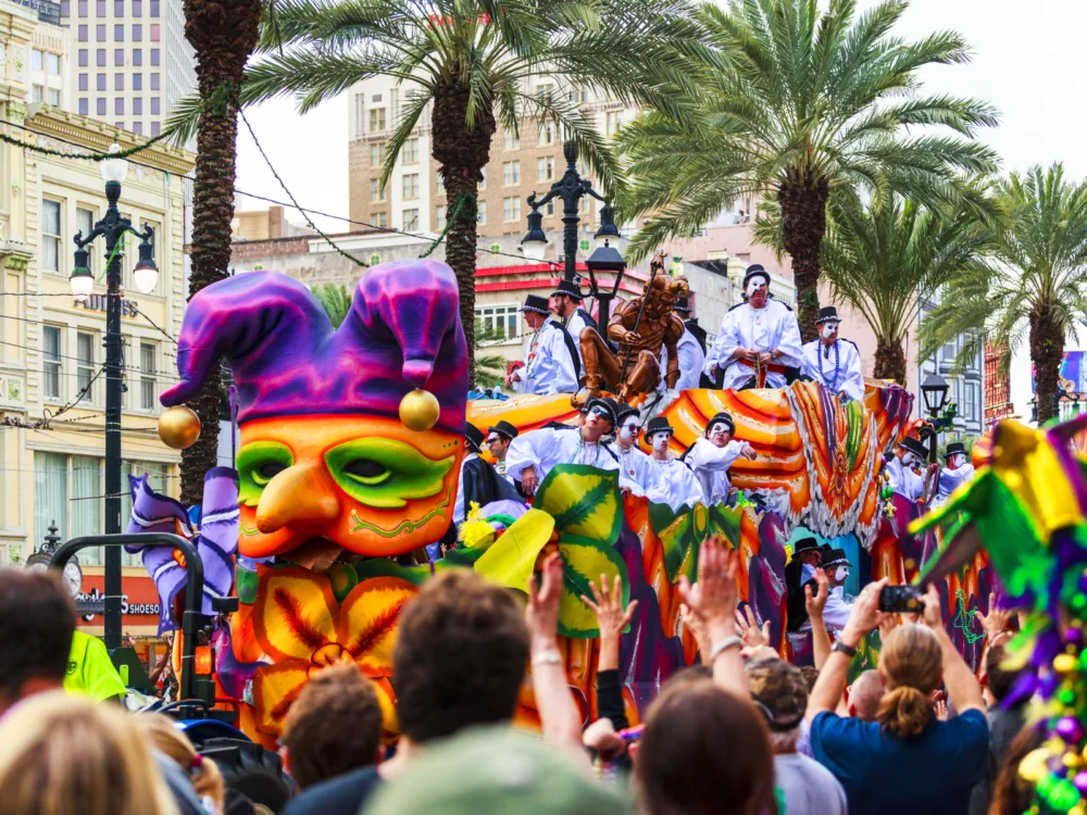 For a roundup of the best hotels in New Orleans, a photo of the parade for Mardi Gras pictured with bright decorations and jester hats